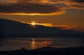 Golden reflections of the sun as sunset on the low tide of Pegwell Bay. The sun is moving behind a cloud and has sun rays Royalty Free Stock Photo