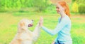 Golden Retriever dog giving paw to hand high five owner woman on the grass training in the park Royalty Free Stock Photo