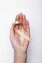 Golden ribbon in hand, symbol childhood cancer, peach uterine ca