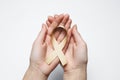 Golden ribbon in hands, symbol childhood cancer, peach uterine c