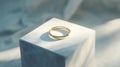 A golden ring resting on a white cube with soft shadows around it all Royalty Free Stock Photo