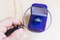 Golden ring with topaz in a blue gift box under a magnifying glass