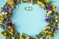 Golden rings with colored flowers on blue background composition, wedding template Royalty Free Stock Photo