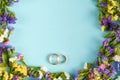 Golden rings with colored flowers on blue background composition, wedding template Royalty Free Stock Photo