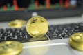 Golden Ripple coin with gold coins lying around on a black keyboard of silver laptop and diagram chart graph on a screen Royalty Free Stock Photo