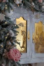 Golden rocking horse toy behind the glass of cupboard, decorated with snowy fir branches and icy roses, snowflakes and icycles