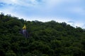 Golden sacred rock at Wat Thewarup Song Tham, Thailand surrounded by forest under the blue sky.