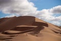 Golden sand dune 7 and white clouds on a sunny day in the Namib desert. Fantastic place for travelers and photographers Royalty Free Stock Photo