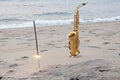 The golden saxophone alto stands on the sand and on the shore, against the background of the sea and Bengal lights. Romantic