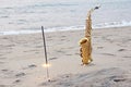 The golden saxophone alto stands on the sand and on the shore, against the background of the sea and Bengal lights. Romantic