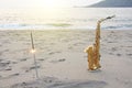 The golden saxophone alto stands on the sand and on the shore, against the background of the sea and Bengal lights. Romantic