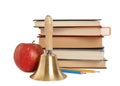 Golden school bell with wooden handle, apple and stack of books on white background Royalty Free Stock Photo