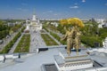 Golden sculpture of Worker and female Collective farmer with golden sheaf of wheat  with VDHKh city park and pavilions Royalty Free Stock Photo