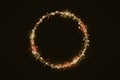 Golden shimmering circle of glittering particles on black background, copy space