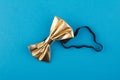 Golden bow tie on blue background