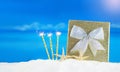 Golden shiny box with silver bow, candles with flames and starfish on sand of beach