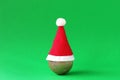 Golden shiny Christmas ball with Santa Claus red hat on green background with copy space. Minimal Christmas and New Year concept Royalty Free Stock Photo