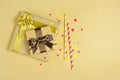 Golden shiny classic gift box with brown satin bow and cocktail straws with confetti in the shape of stars as attributes of party Royalty Free Stock Photo