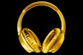 Golden shiny wireless headphones on black background isolated closeup, expensive gold metal bluetooth headset, yellow earphones