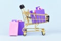 Golden shopping cart filled with pink and purple paper shopping bags Royalty Free Stock Photo