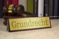 Golden sign with law books and gavel with the german word for fundamental right - grundrecht on a wooden table