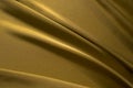 Golden silk satin fabric background. Luxurious background for your design with copy space. Liquid wave or wavy folds. Royalty Free Stock Photo