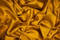 Golden silk satin fabric. Luxurious bright background for your design. Beautiful folds on shiny gold fabric.