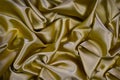 Golden silk satin fabric. Luxurious bright background for your design. Beautiful folds on shiny gold fabric. Royalty Free Stock Photo