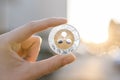 Golden silver Ripple coin in hand on a blurred sunset background. Hand holding a crypto currency virtual money