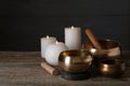 Golden singing bowls, mallets and burning candles on wooden table, space for text