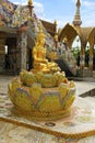 Golden sitting statue of Lord Buddha, sitting in a lotus, decorated with beautiful, colorful mosaic tiles at the entrance of at Ph