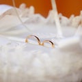 Golden smoth wedding rings in white silk basket with pearls and ribbons
