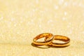 Golden sparkling glitter bokeh background with golden wedding rings Royalty Free Stock Photo