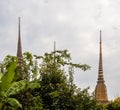 Golden spires of the Wat Pho temple revealed behind lush greenery in Bangkok, Thailand