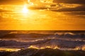 Golden splashing waves and sunrise over sea water