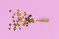 Golden star confetti splashing out of Champagne bottle on pink background Royalty Free Stock Photo