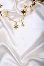 Golden stars and spangles on white silk Royalty Free Stock Photo