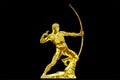 Golden statue of an antique bowman or an archer on a black background. Shining ancient warrior with bow profile view