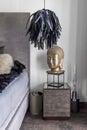 Statue with a buddha face next to fancy chandelier in trendy interior