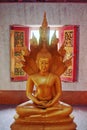 Golden statue of a sitting Buddha protected by Naga serpents