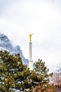 Golden statue and white spire of church against clouds and snowy mountain