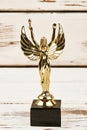 Golden statuette on wooden backdrop.