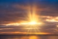 Golden Sun Rays Shining through Dark Clouds onto the Sea Royalty Free Stock Photo