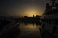 Golden sun sets ehind the cathedral viewed between two boats at