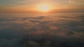 Golden sun setting down over clouds covering nature. Aerial view bright sunset