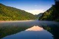 The golden sun shine on the green trees are on the hill,a reflection on the Calm lake,under the blue sky and white clouds