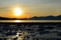 Golden sunrise over blue fjord and snowy mountain with reflection on thick ice Royalty Free Stock Photo