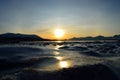 Golden sunrise over blue fjord and snowy mountain with reflection on thick ice Royalty Free Stock Photo