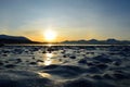 Golden sunrise over blue fjord and snowy mountain with reflection on thick ice Royalty Free Stock Photo