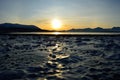 Golden sunrise over blue fjord and snowy mountain with reflection on thick frozen sea shore ice Royalty Free Stock Photo